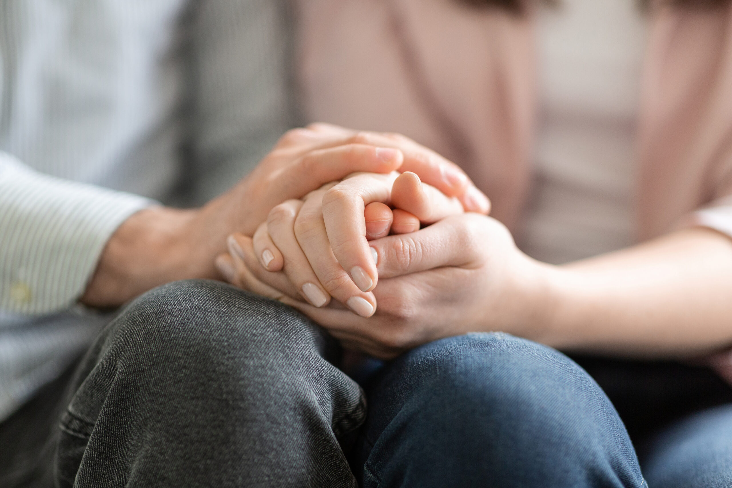 Close up of man and woman holding hands, giving psychological support