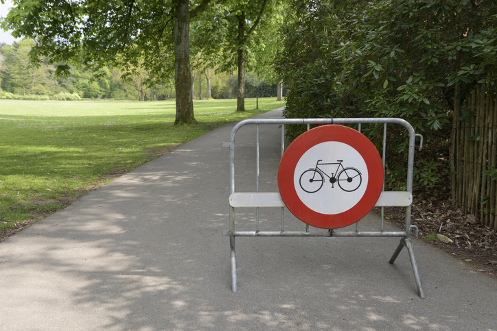 Portable fencing in a park with a warning sign - bicycle access prohibited. Path only for walking